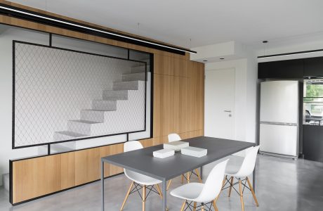 Modern dining room with sleek gray table, white chairs, and geometric wall art.