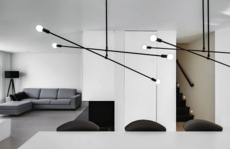 A modern, minimalist living room with striking black lighting fixtures and clean lines.