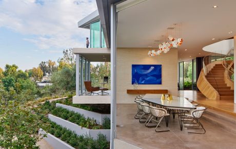 A modern, open-concept dining area with floor-to-ceiling windows overlooking lush, landscaped gardens.