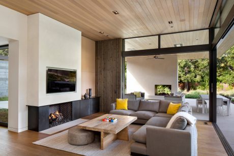Cozy living room with wood-paneled ceiling, fireplace, and modern furniture arrangement.