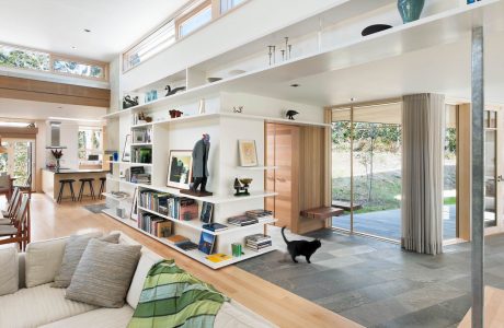 Open-concept living space with tall ceilings, built-in shelves, and sliding glass doors leading to a verdant outdoor area.