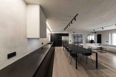 Modern kitchen and dining area featuring sleek black cabinetry, track lighting, and wood flooring.