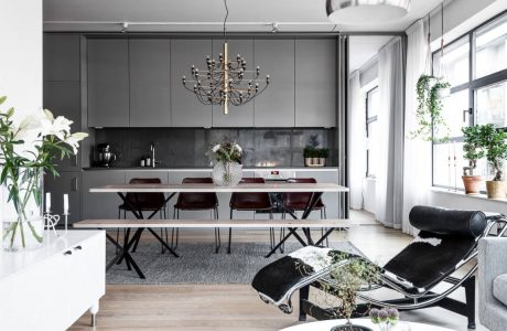 Chic modern kitchen-dining area with sleek gray cabinetry, industrial lighting, and plush seating.