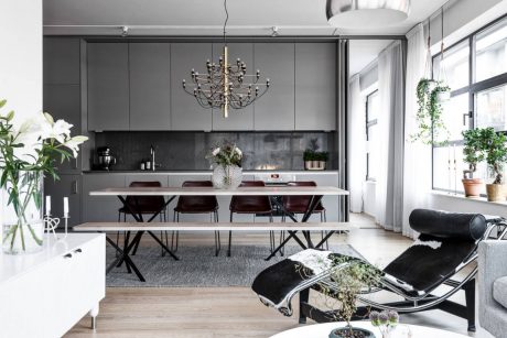 Chic modern kitchen-dining area with sleek gray cabinetry, industrial lighting, and plush seating.