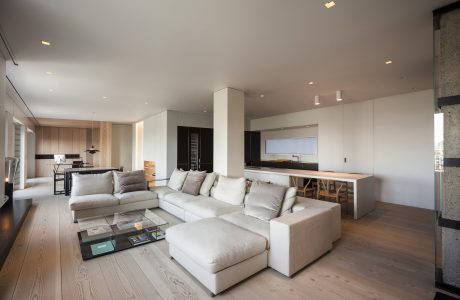 Bright, open-concept living room with plush, modular sofa, wood flooring, and integrated kitchen.