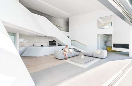 Minimalist, open-concept living space with modern furniture, sleek kitchen, and high ceilings.