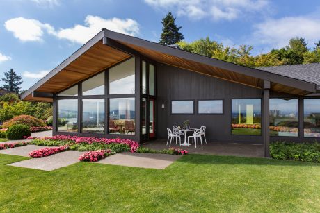 Modern two-story home with sleek black exterior, large windows, and covered patio.