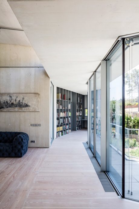 Sleek, modern hallway with built-in bookshelves and floor-to-ceiling windows offering scenic views.