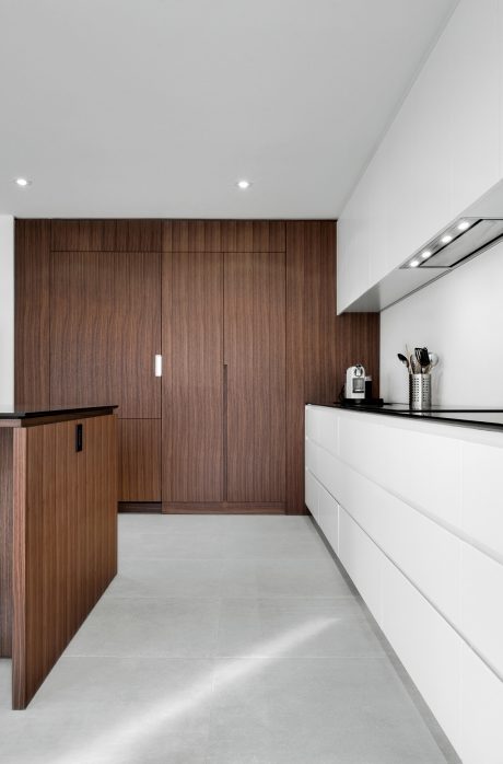A modern kitchen with clean lines, warm wood cabinetry, and a sleek white countertop.