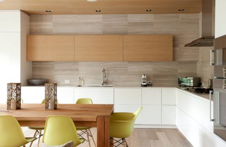Minimalist kitchen with wood-paneled walls, neutral tones, and pops of yellow chairs.