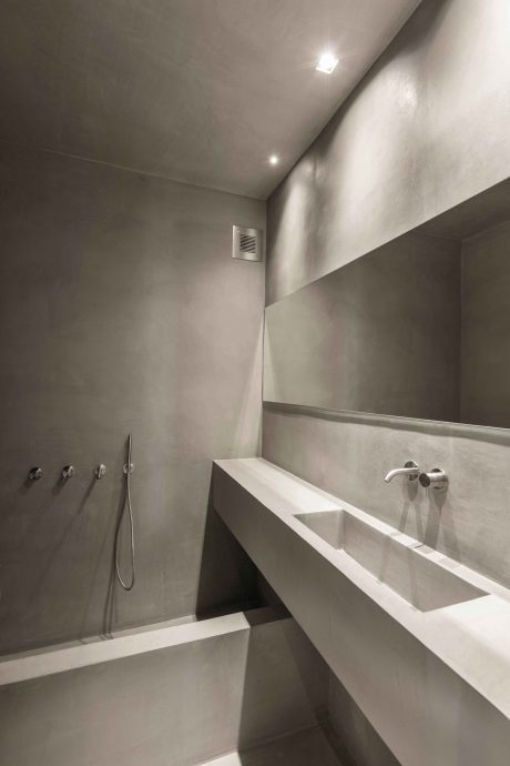 Minimalist bathroom with white concrete sink and recessed lighting, modern design.