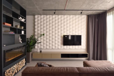 A modern living room with a concrete ceiling, hexagonal wall tiles, and a minimalist TV console.