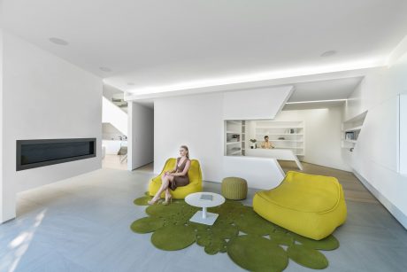 Modern open-plan living space with vibrant yellow furniture and organic-inspired flooring.