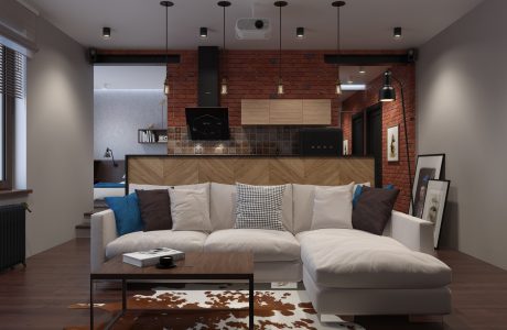 A modern, cozy living room with exposed brick walls, wooden kitchen cabinets, and a plush sectional sofa.