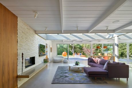 Spacious midcentury-inspired living room with wood-paneled walls, vaulted ceilings, and contemporary furnishings.