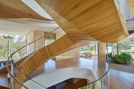 Sleek wooden architectural design with curved glass walls and ceiling.
