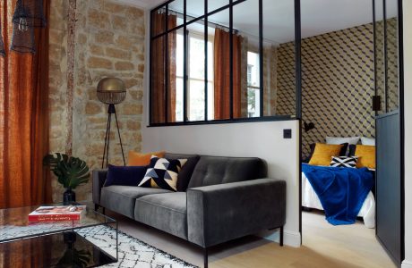 A modern loft with stone walls, steel-framed windows, and a plush gray sofa.