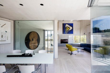 Minimalist living room with sleek furniture, modern artwork, and large glass windows.