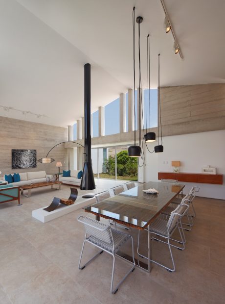 Expansive living area with concrete walls, modern lighting fixtures, and sleek furnishings.