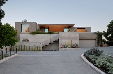 Modern concrete and wood luxury home with tiered landscaping and cacti garden.