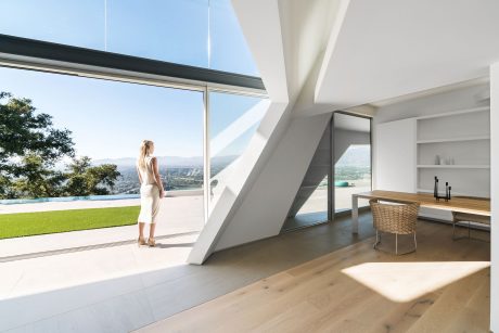 A modern, airy interior with large windows overlooking a lush outdoor landscape.