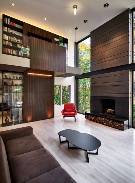 Striking modern interior with dark wood paneling, red accent chair, and floor-to-ceiling windows.