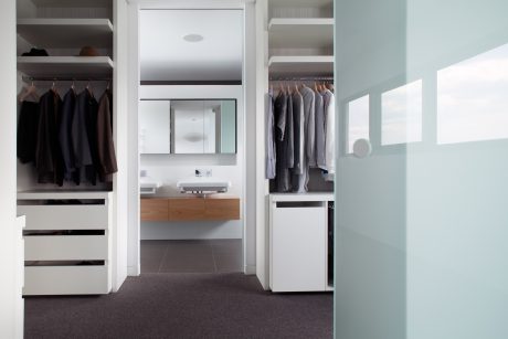 Modern closet with sleek storage solution, minimalist vanity, and glass partitions.
