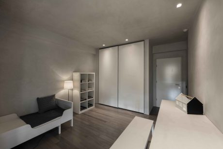 Minimalist bedroom with built-in wardrobe, shelving, and neutral tones throughout.