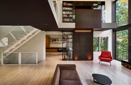 A modern, open-concept space featuring a sizable bookcase, hardwood floors, and sleek furnishings.