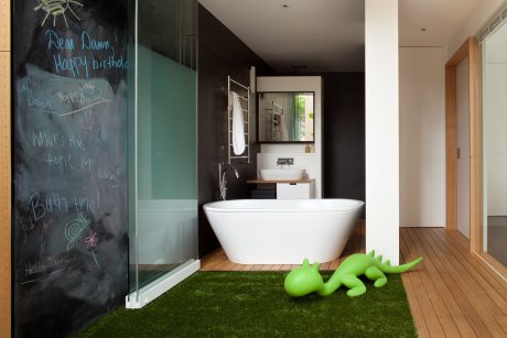 Sleek modern bathroom design with freestanding tub, green accent pieces, and chalkboard wall.