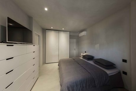 Minimalist bedroom with gray walls, built-in storage, and recessed lighting.