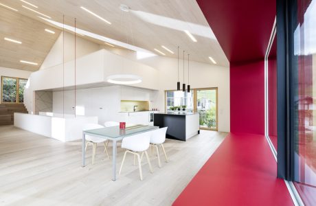 Spacious open-plan kitchen and dining area with modern, minimalist design and vibrant red accent wall.