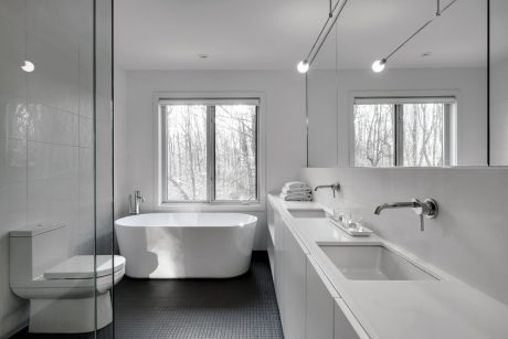 Modern, minimalist bathroom with freestanding bathtub, glass shower, and sleek vanity.