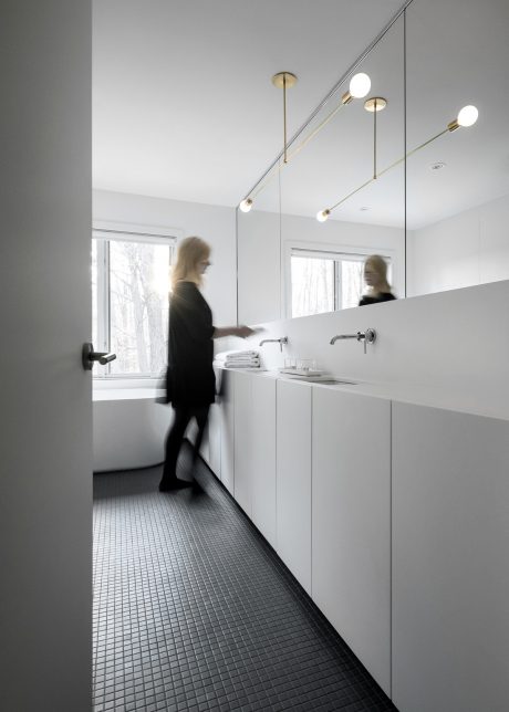 Minimalist bathroom interior with sleek white cabinetry, mirror, and linear lighting.