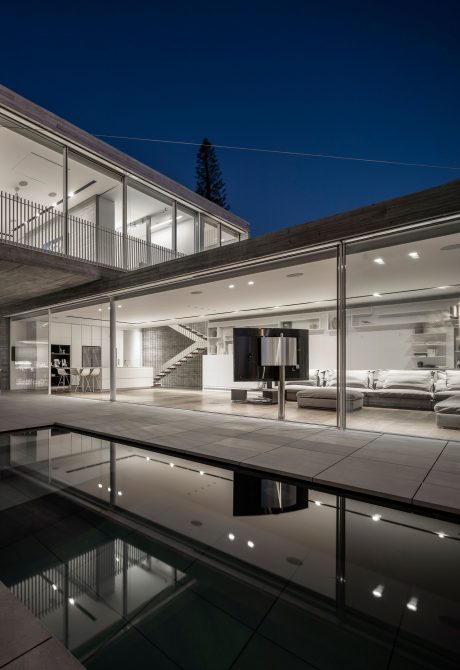 Modern minimalist architecture with expansive glass walls, sleek pool, and dramatic lighting.