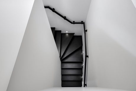 Dramatic spiral staircase with sleek black railings in modern architectural space.