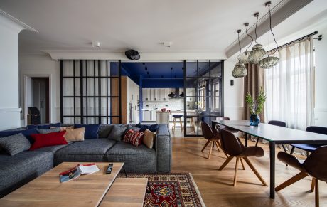 Modern apartment interior with open-concept living and dining areas, featuring glass partitions and eclectic furnishings.