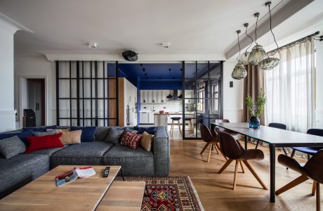 Modern apartment interior with open-concept living and dining areas, featuring glass partitions and eclectic furnishings.
