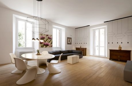 A spacious, modern living room with geometric light fixtures, wooden floors, and minimalistic furniture.