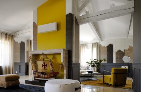 Spacious living room with wood-paneled walls, vibrant yellow accents, and unique architectural elements.
