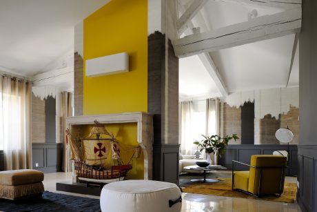 Spacious living room with wood-paneled walls, vibrant yellow accents, and unique architectural elements.