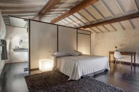 Cozy bedroom with wooden beams, minimalist design, and textured rug.