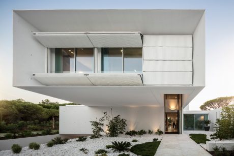 This modern building features a striking white facade with a cantilevered second floor and large windows.