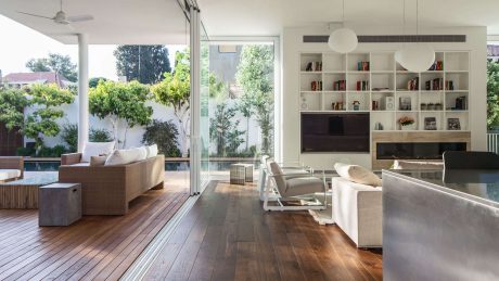 Bright, open-plan living space with expansive windows, wooden floors, and built-in shelving.