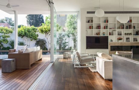 Bright, open-plan living space with expansive windows, wooden floors, and built-in shelving.