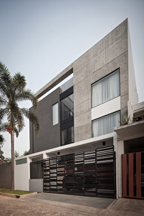 Modern concrete facade with geometric patterns and landscaping elements.