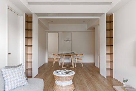 Minimalist, open-plan room with wooden furniture, shelving, and hardwood flooring.