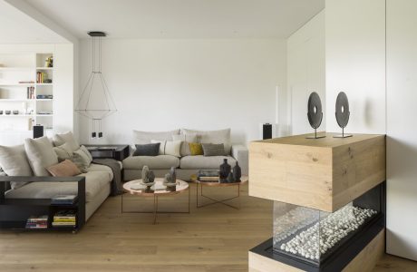 Spacious modern living room with neutral tones, geometric decor, and natural wood furnishings.