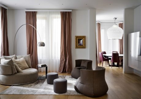 Elegant living room with plush seating, ornate chandelier, and wood-paneled walls.