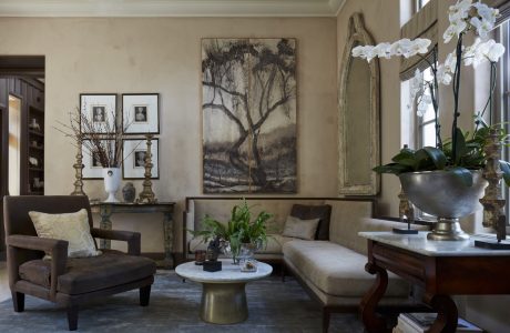 Cozy living room with elegant furnishings, artwork, and potted plants, creating a warm ambiance.